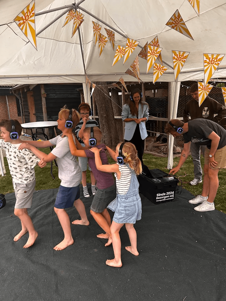 Kinderfeestje met silent disco hoofdtelefoons, dansende kinderen en vrolijke sfeer.